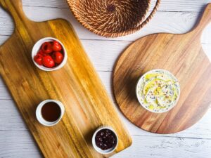 Wooden charcuterie board with small dishes and bowls of condiments and pickled items.