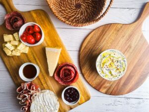Wooden charcuterie boards with small dishes, cheeses, and meats.