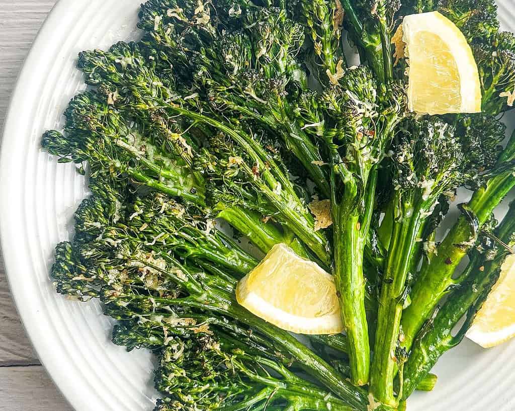 Charred broccolini with parmesan and lemon in a white bowl.