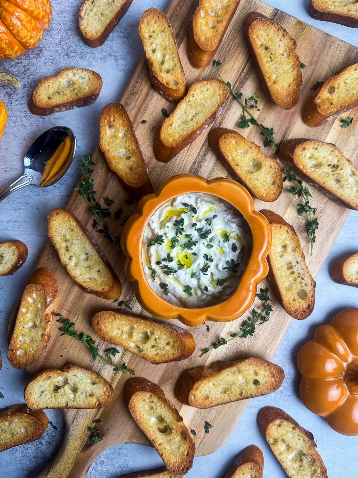 Truffle burrata dip on a board with crostini and fresh thyme.
