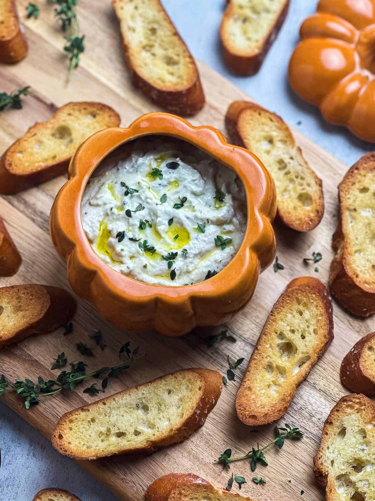 Truffle burrata dip on a charcuterie board with crostini and fresh thyme.