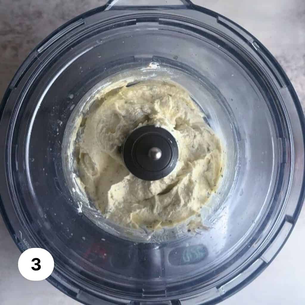 Whipped burrata truffle dip in the bowl of a food processor.