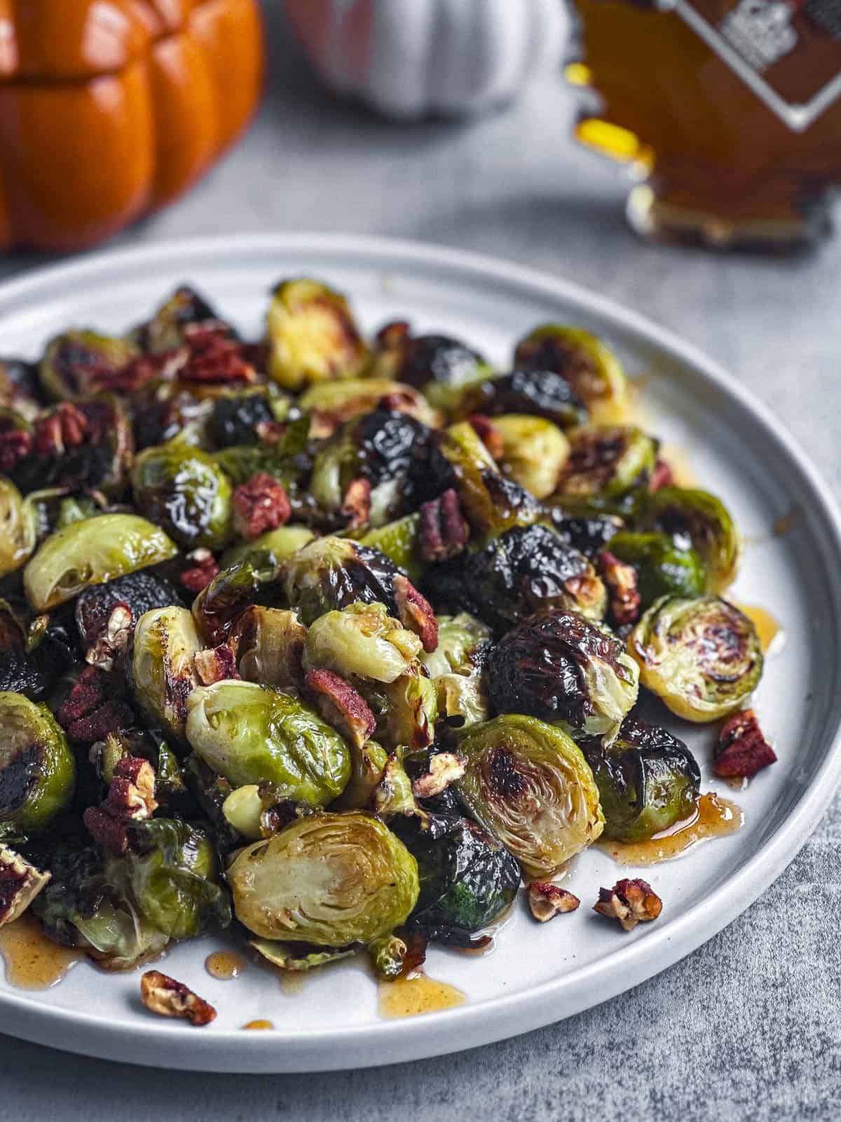 Maple sriracha brussels sprouts with pecans on a white plate.