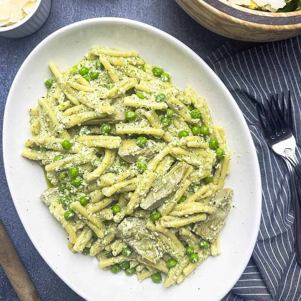 Ricotta pesto pasta with a grainier ricotta texture on a white oval plate.