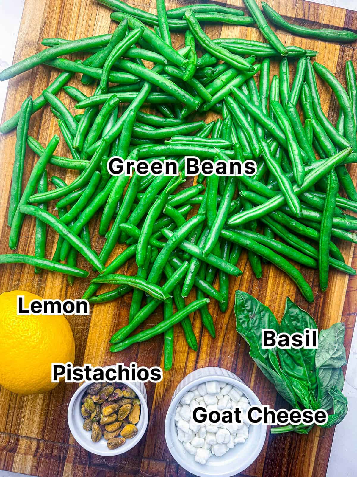 Key ingredients for green bean salad on a wooden cutting board.