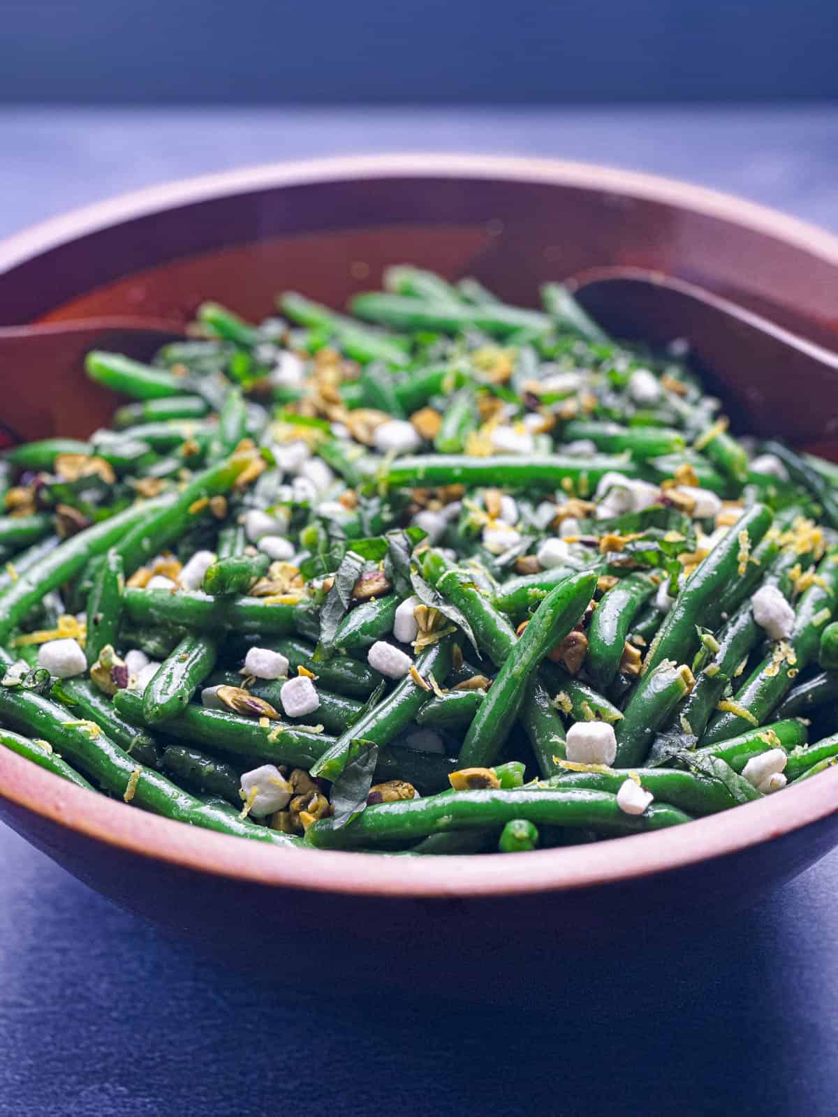Side view of green bean salad in an Acacia wood bowl.