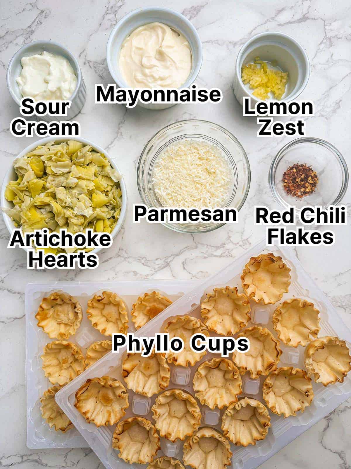 Ingredients for artichoke phyllo cup bites laid out onto a counter top.