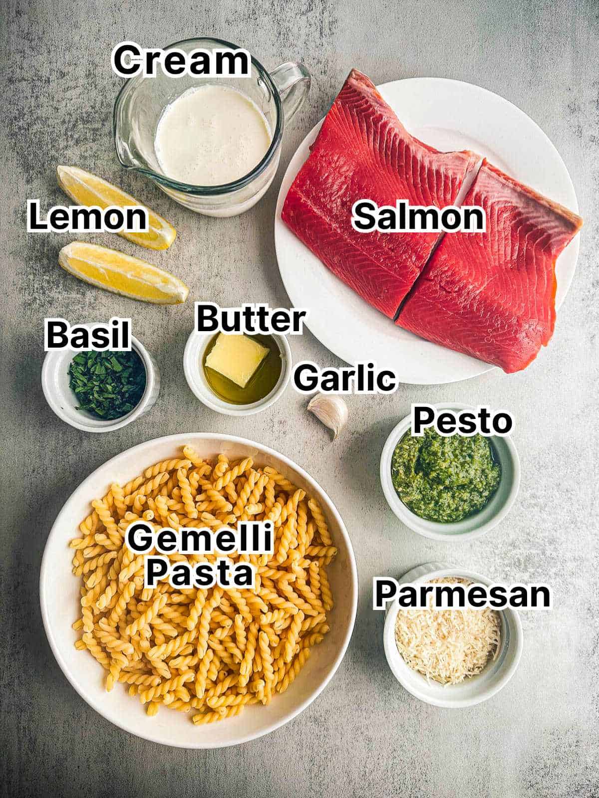 Gemelli pasta, salmon, cream, pesto and other ingredients for pesto salmon pasta.