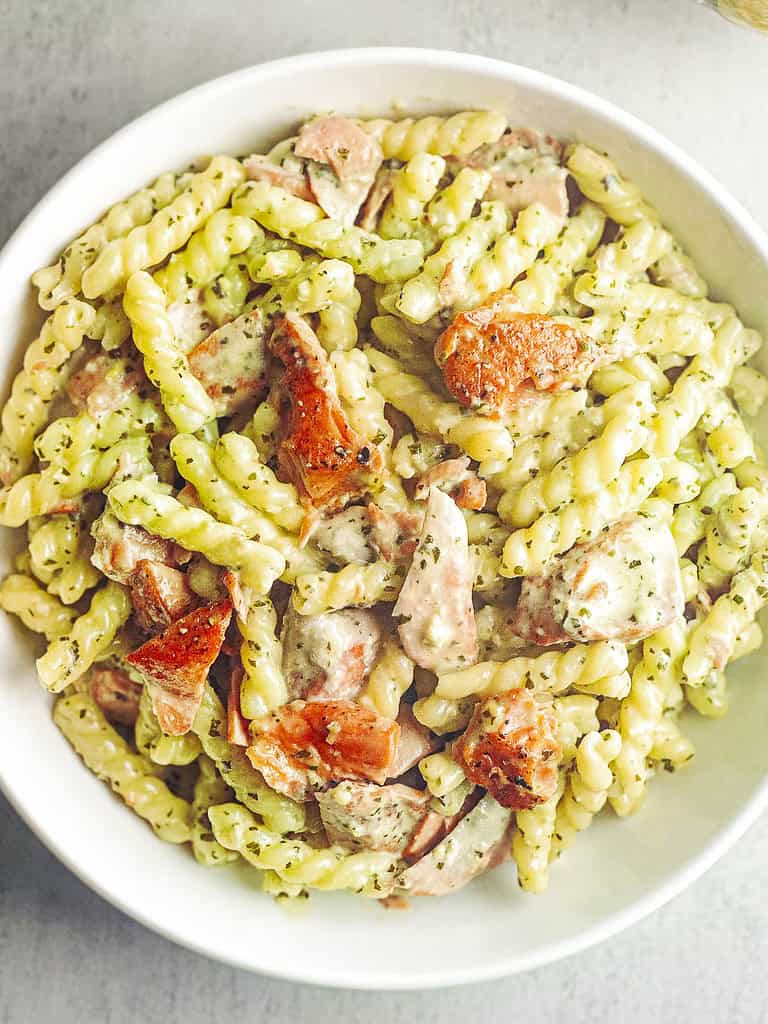 Pesto salmon pasta in a white bowl.