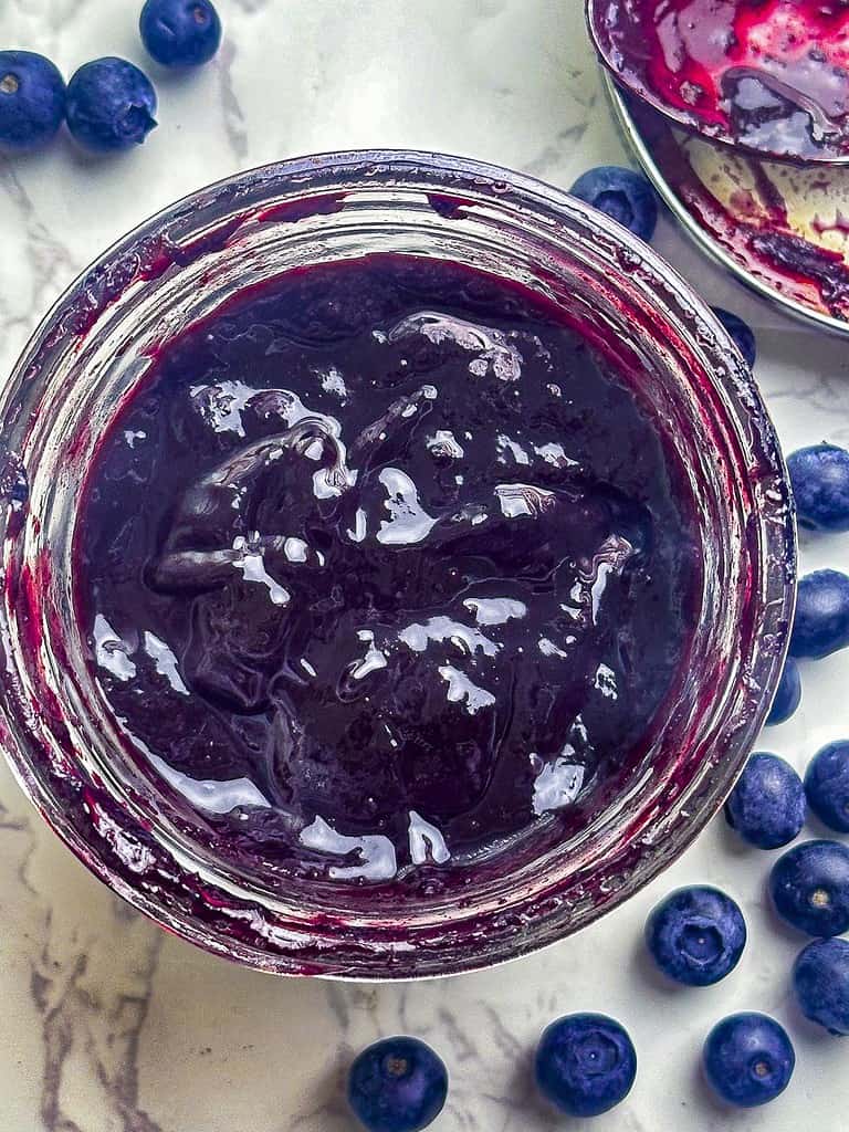 Blueberry BBQ sauce in a mason jar with blueberries on the side.