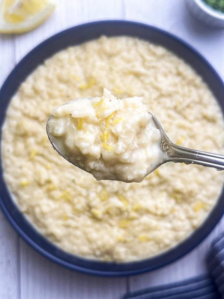 Creamy lemon risotto in a blue bowl with a spoonful.