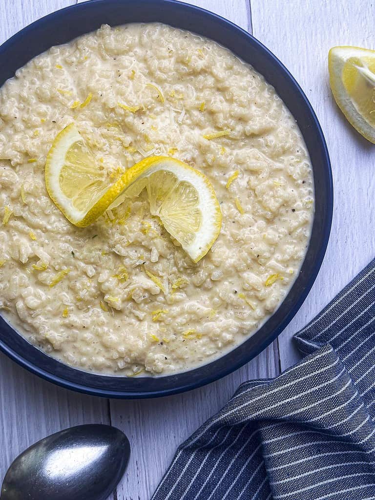 Creamy lemon risotto in a blue bowl with a spoon and napkin.