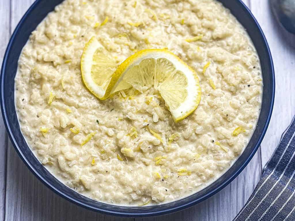 Creamy lemon risotto in a blue bowl with a spoon and napkin.