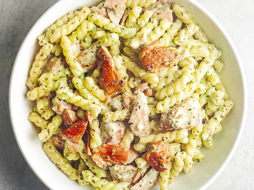 Gemelli pasta with salmon and creamy pesto sauce in a white bowl.