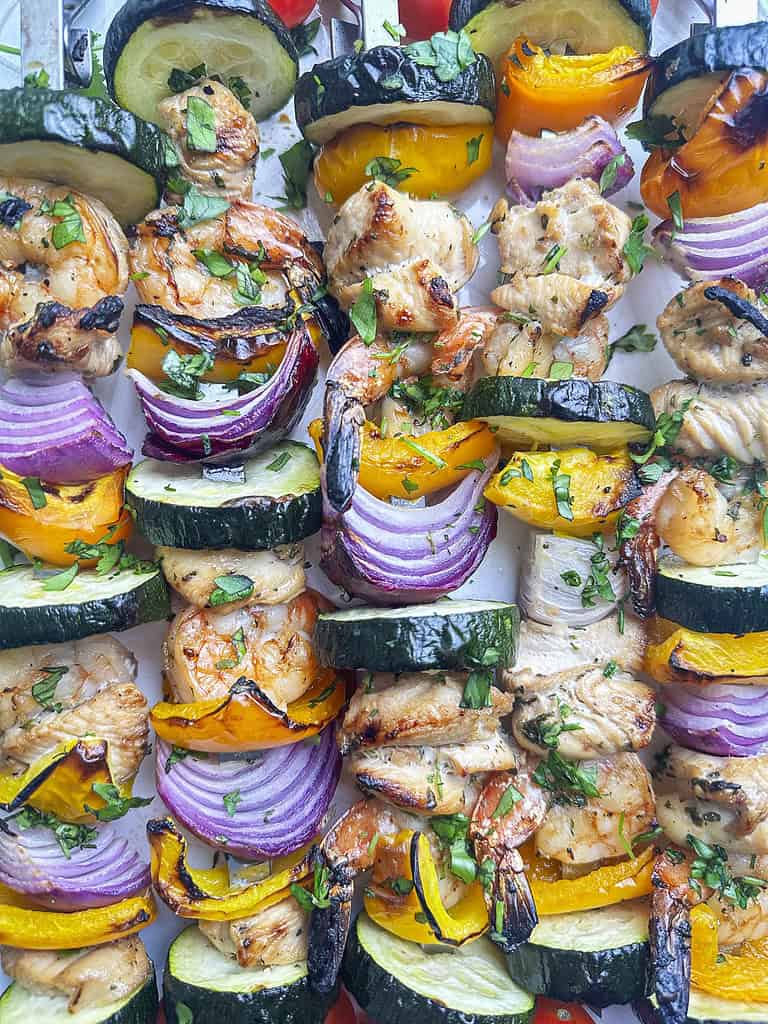 Grilled shrimp and chicken skewers with veggies up close.