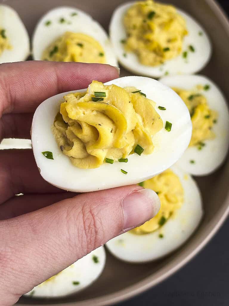 Truffled deviled eggs with fingers holding one over it.
