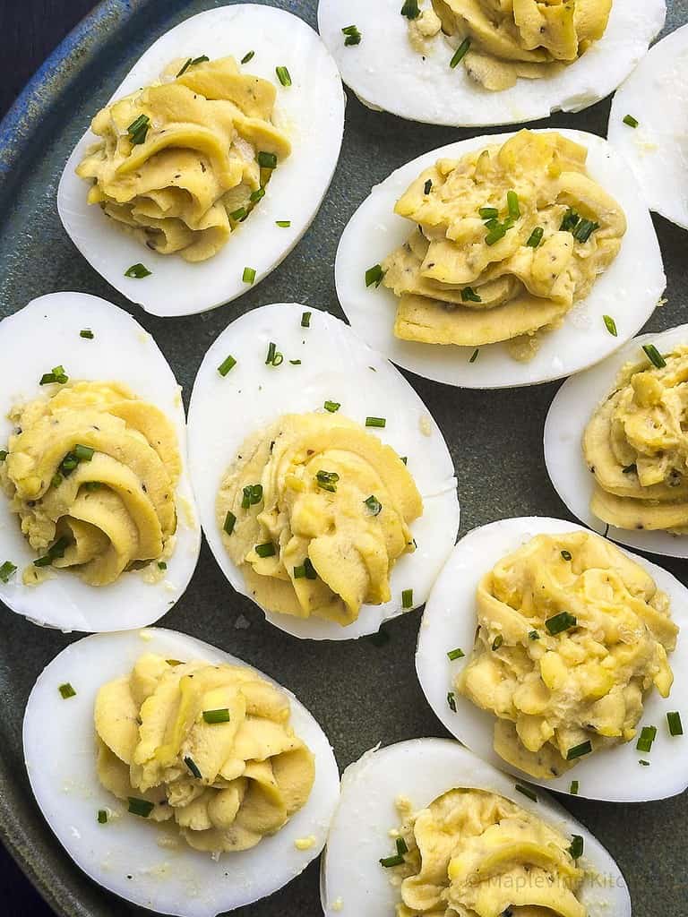 Truffled deviled eggs on a plate with chive garnish.