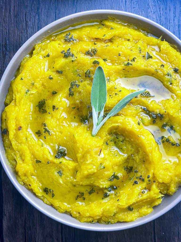 Mashed acorn squash with brown butter and sage in a bowl.