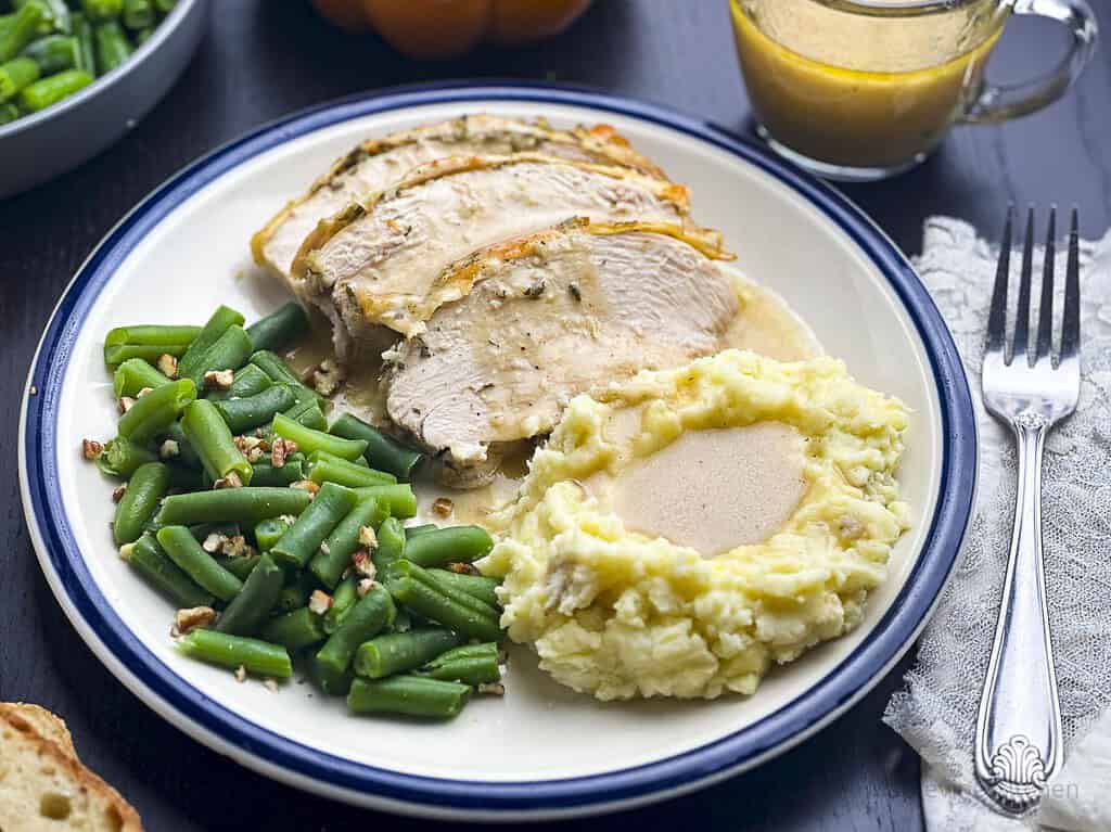 Roast turkey slices with mashed potatoes and gravy on a plate.