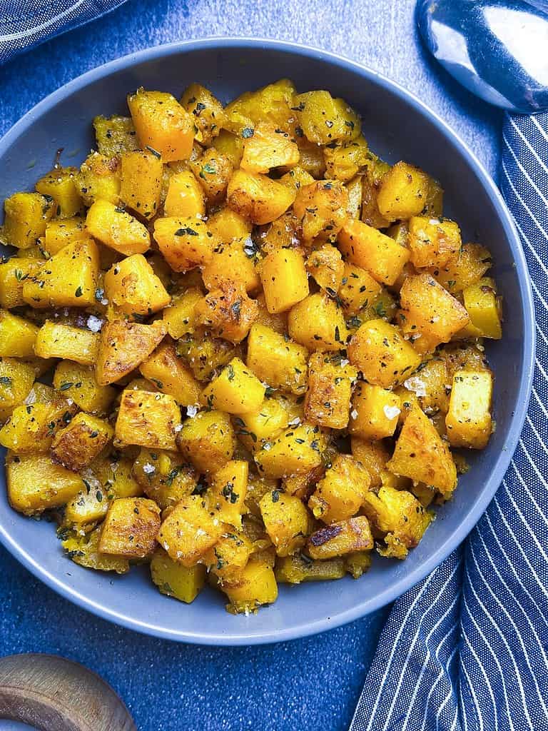 Sauteed butternut squash with seasonings in a bowl.