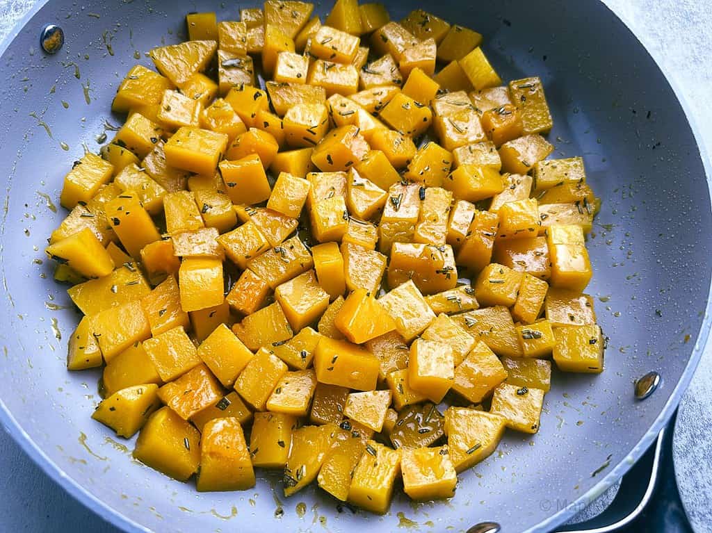 Butternut squash with apple cider glaze in a skillet.