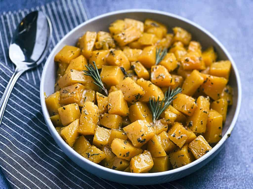 Butternut squash with apple cider glaze in a bowl with a spoon.