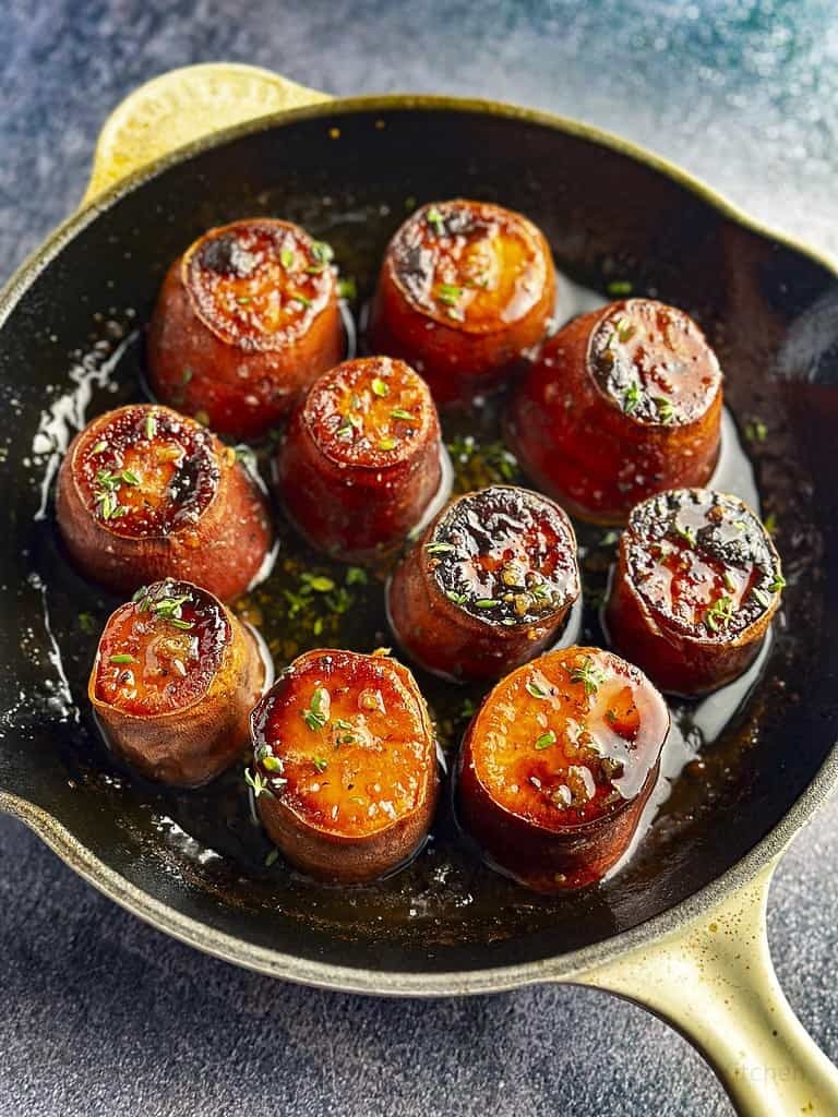 Fondant sweet potatoes with maple thyme glaze in a cast iron skillet.