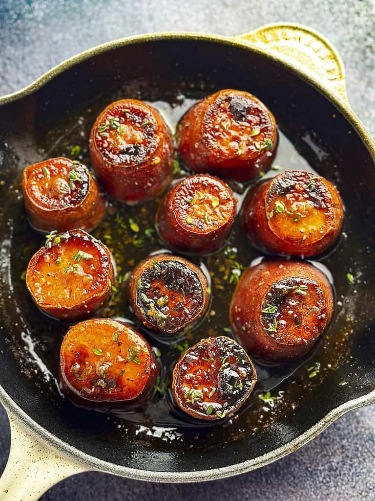 Fondant sweet potatoes in a white enameled cast iron skillet.