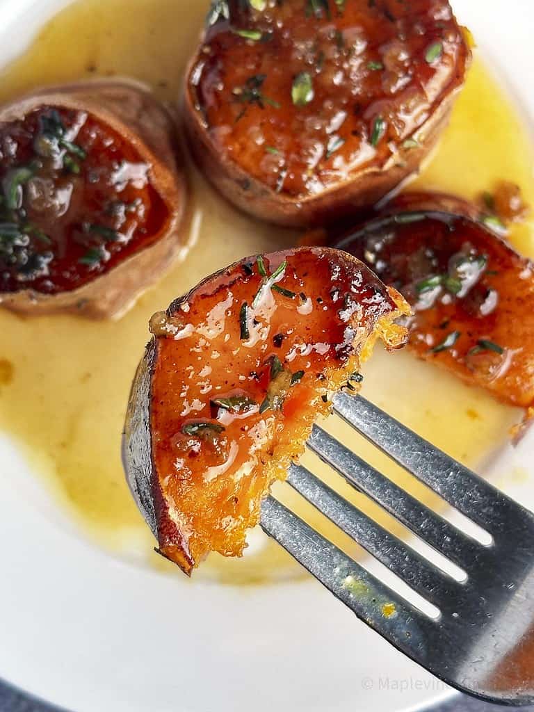 A slice of sweet potatoes fondant on a fork with more potatoes in the background.