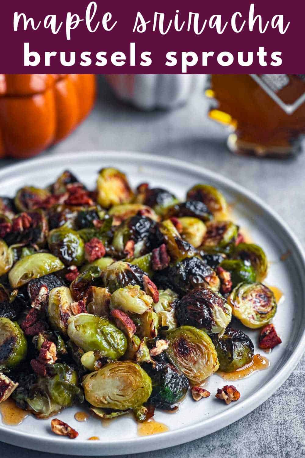 Maple sriracha glazed brussels sprouts with pecans on a round white plate.