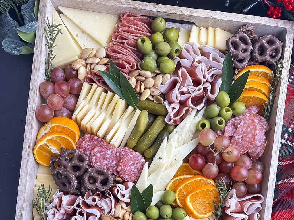 Charcuterie meats, cheese, fruit, and nuts in a wooden tray,