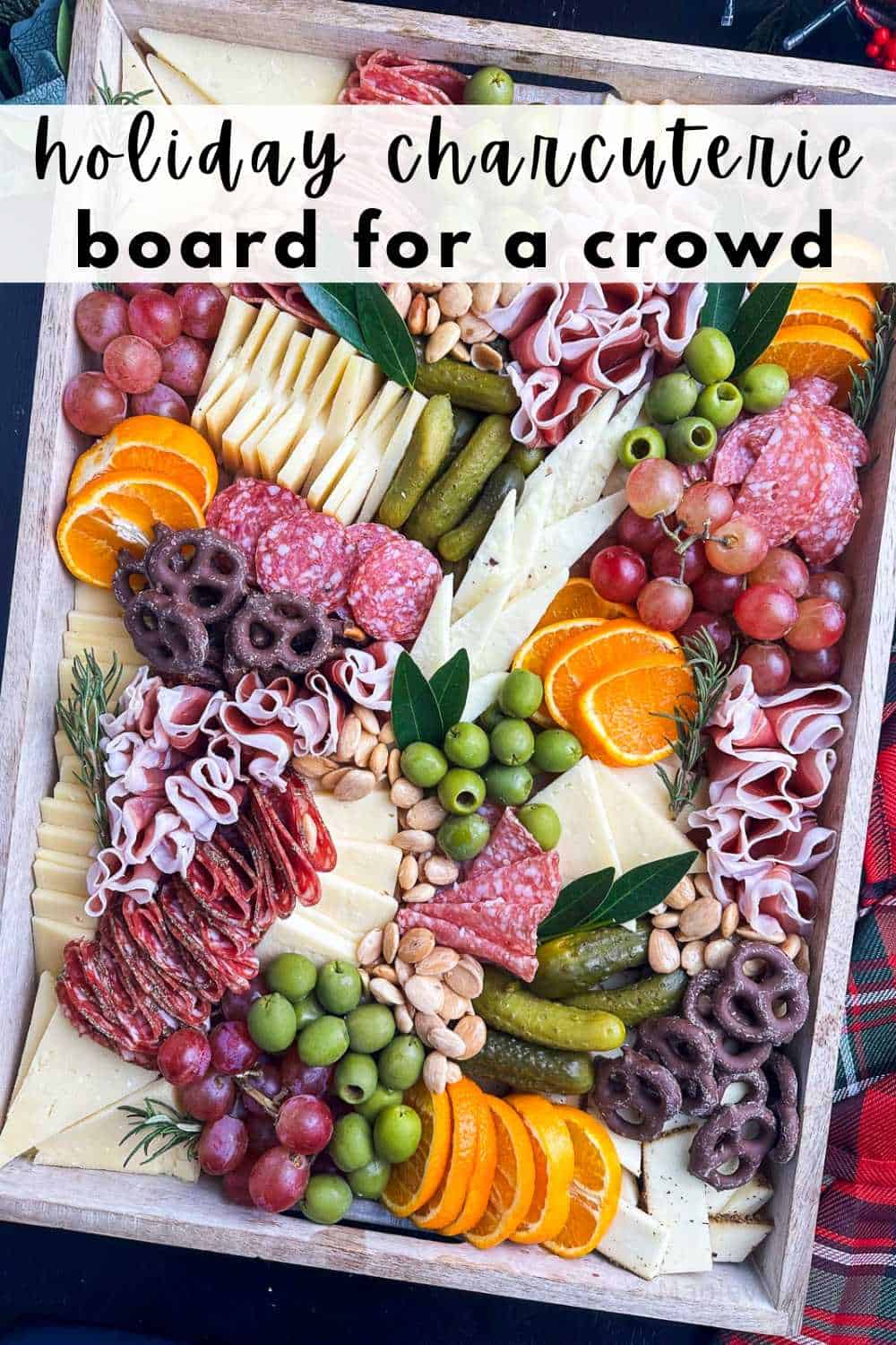 Holiday charcuterie board with cheeses, meats, fruits, and accompaniments with the title a the top.