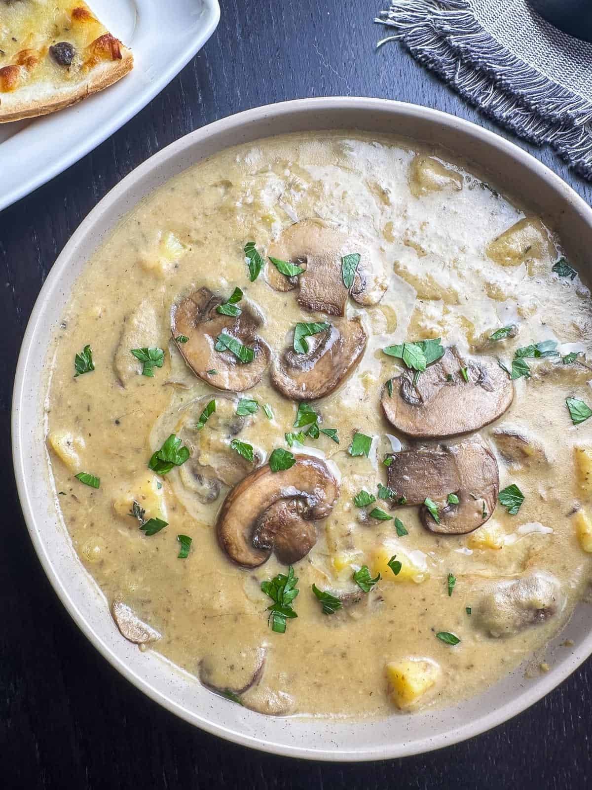 Creamy mushroom and potato soup in a bowl with parsley garnish.