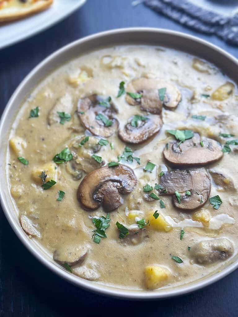 Creamy mushroom and potato soup in a bowl with parsley an truffle oil garnish.