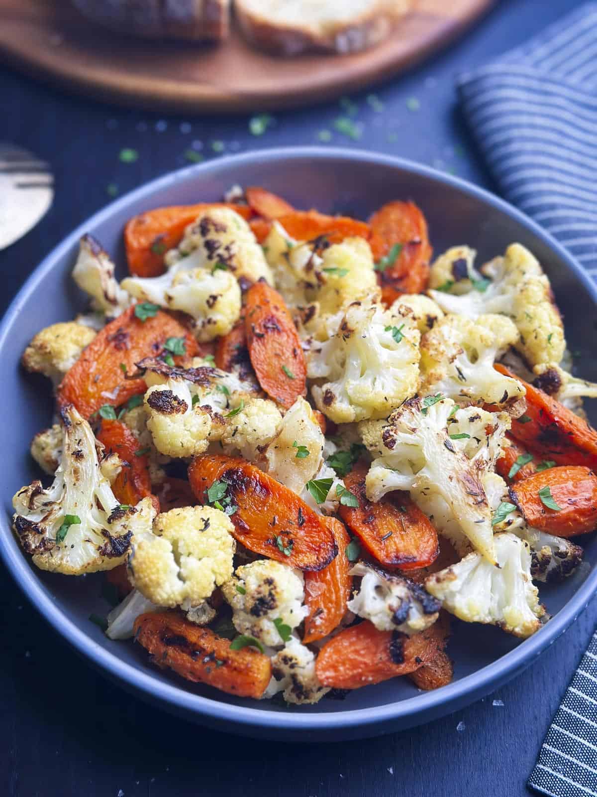 Roasted carrots and cauliflower in a bowl with a napkin on the side.