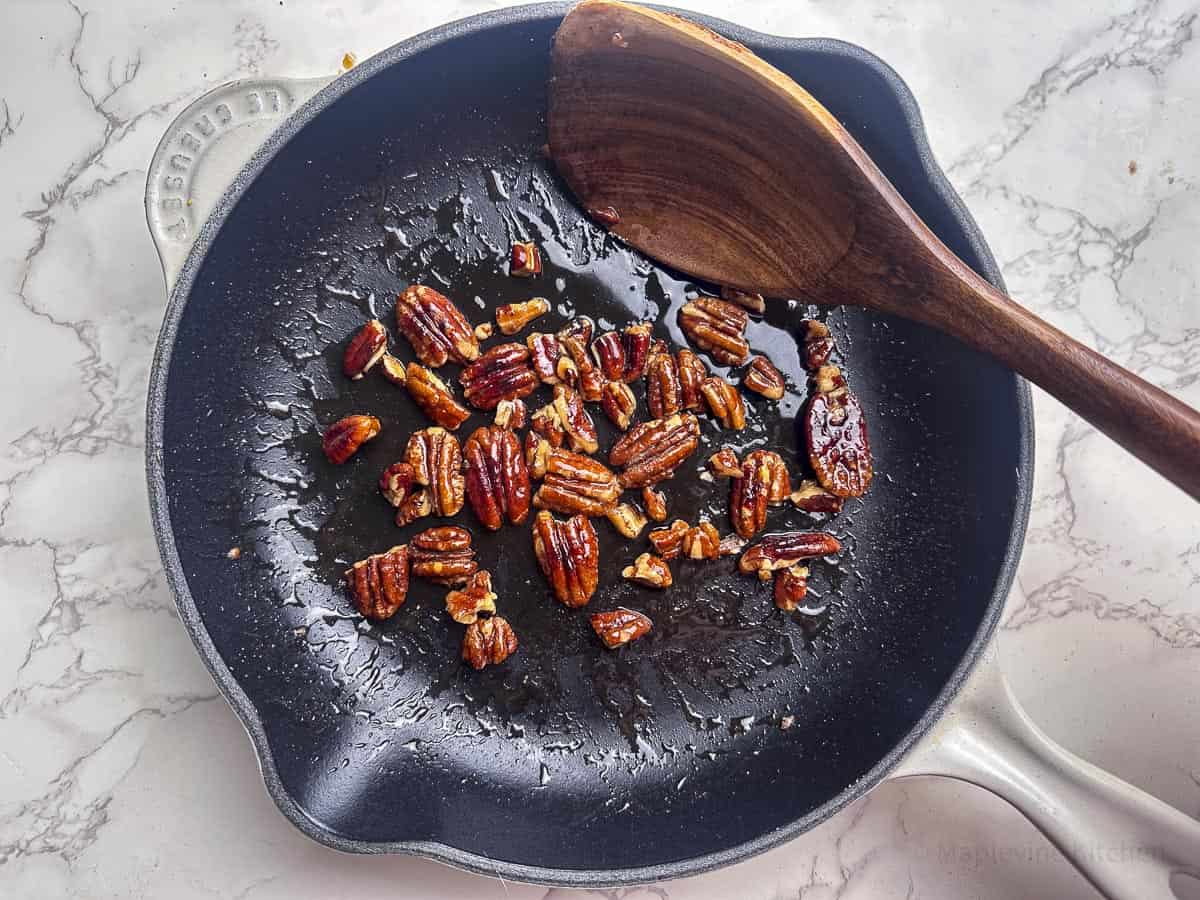 Pecans and maple syrup in a cast iron skillet.