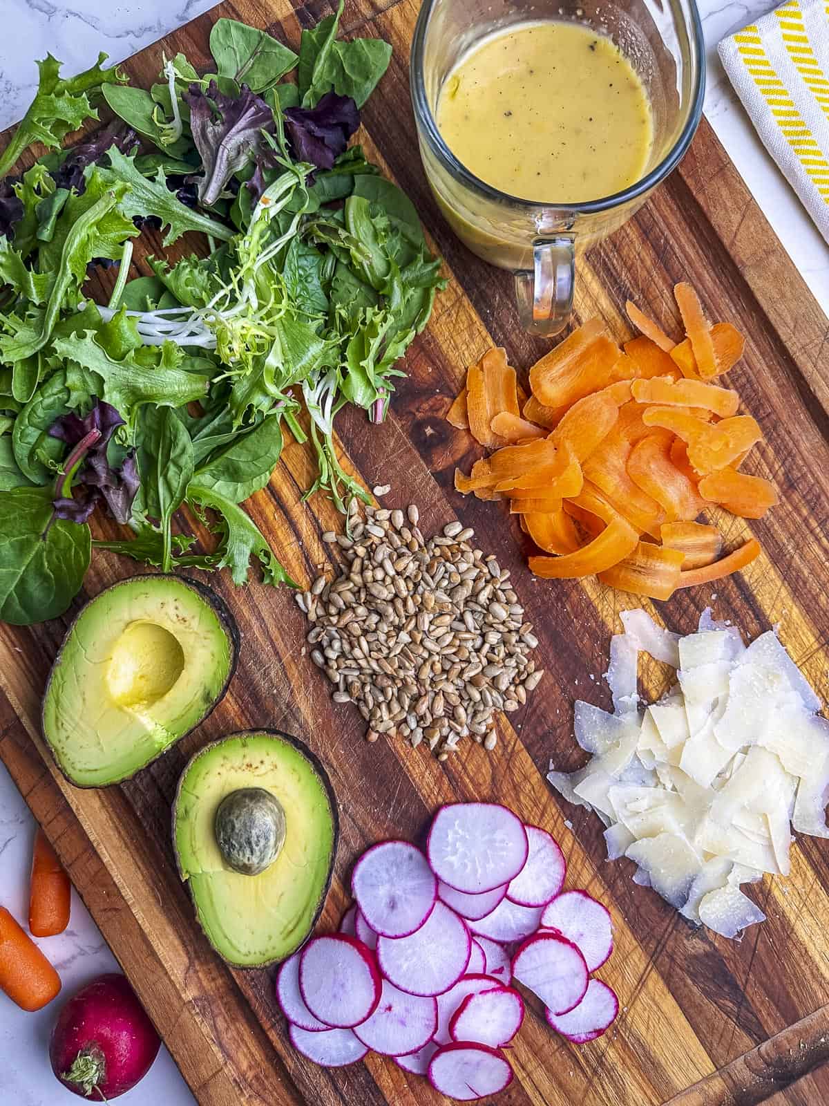 Field greens salad ingredients on a cutting board.