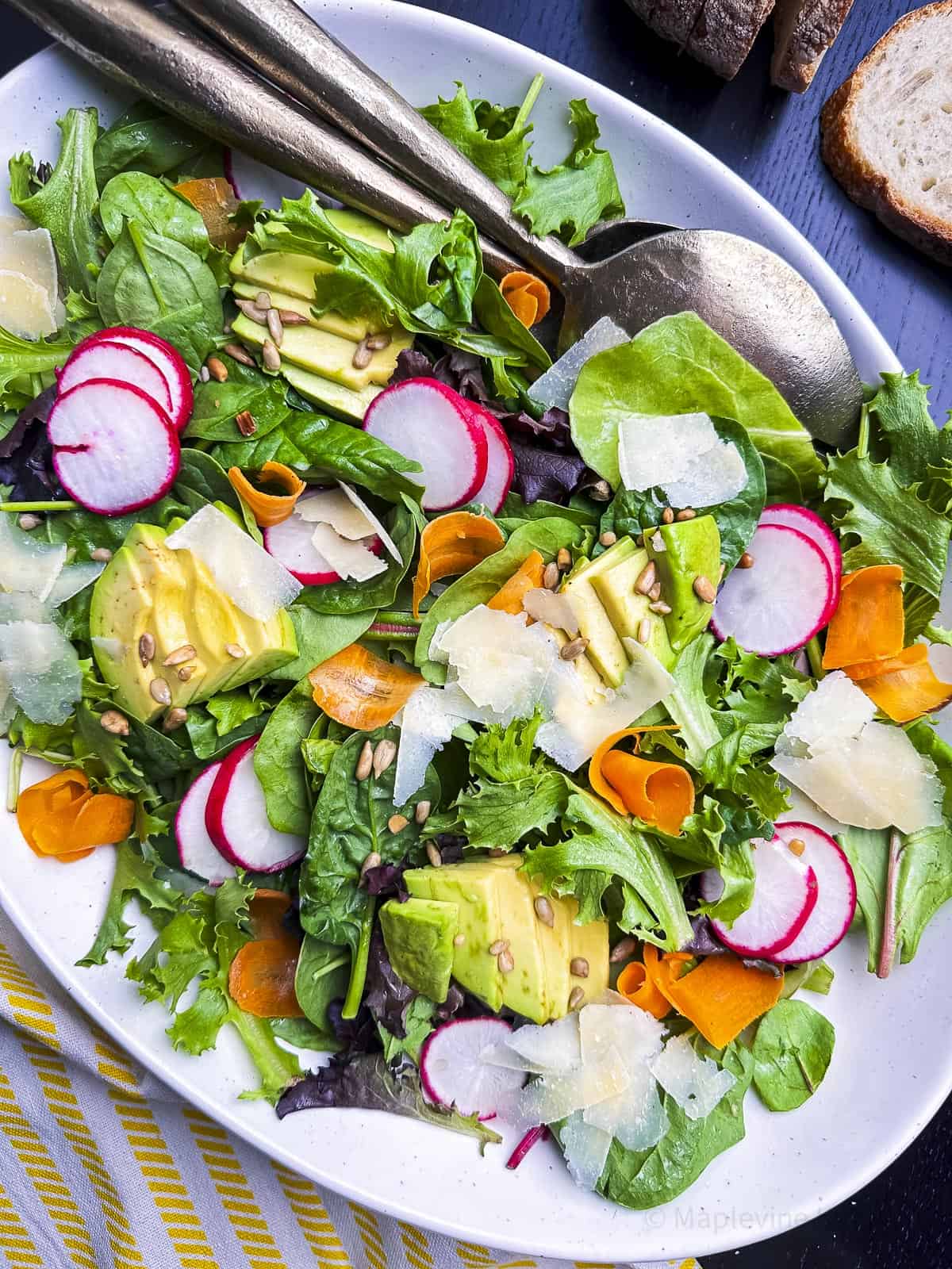 Hero shot of simple field greens salad on a white oval platter.