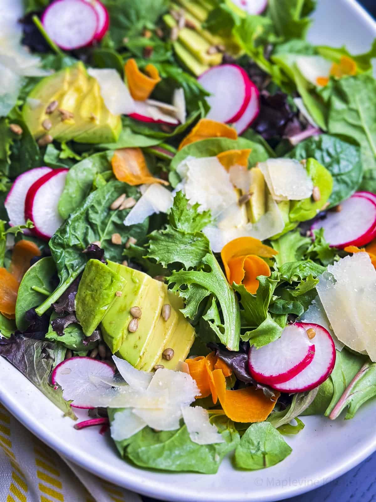 Close up shot of simple field greens salad on a platter.