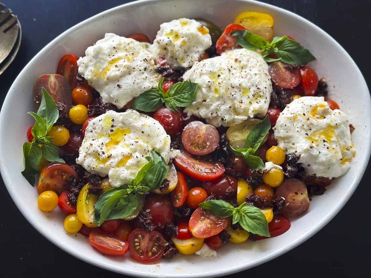 A burrata caprese salad with tomatoes and basil.