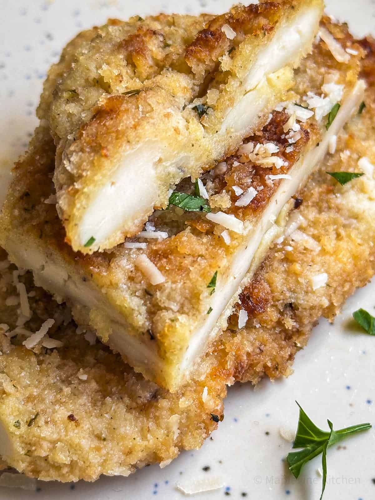 Sliced chicken cutlets stacked on a plate.
