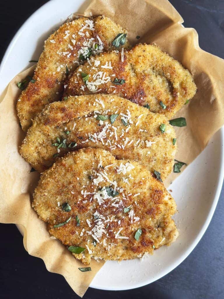 Crispy Italian chicken cutlets on a white plate.