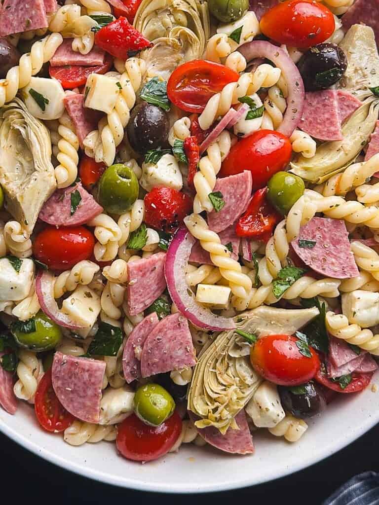 Close up shot of antipasto pasta salad on a white plate.