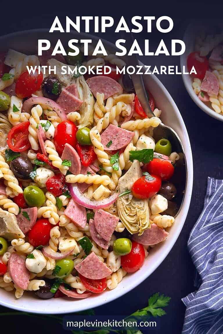 Antipasto pasta salad in a white bowl with a napking on the side.