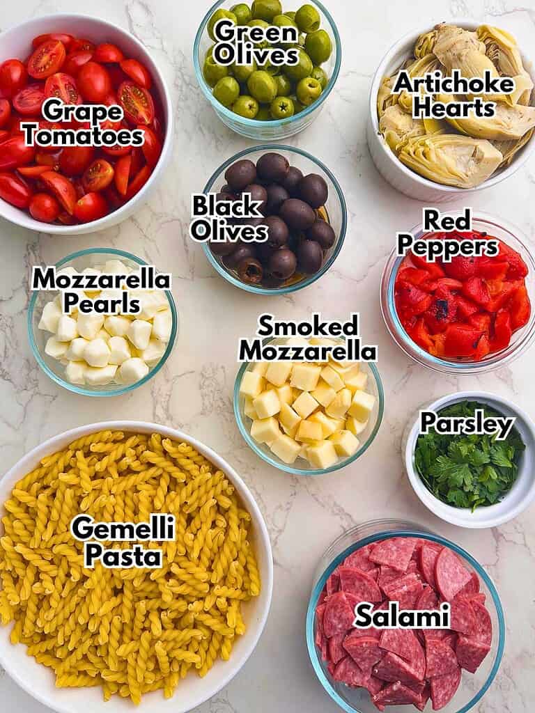 Fresh ingredients for a delicious Italian pasta salad, including vegetables, cheeses, and salami.