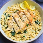 Creamy lemon chicken orzo with the chicken breast sliced on top of the orzo.