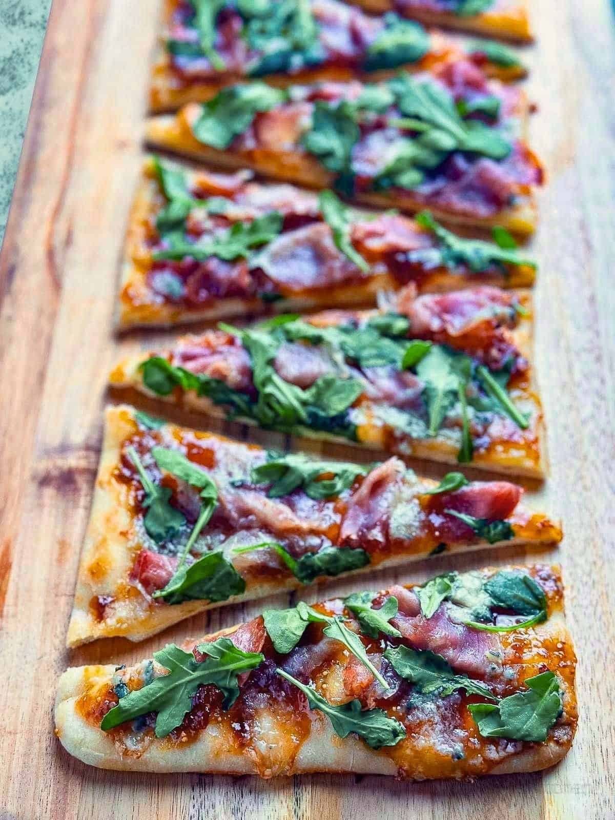 Delicious homemade flatbread pizza topped with fig jam, prosciutto, blue cheese, and fresh arugula.