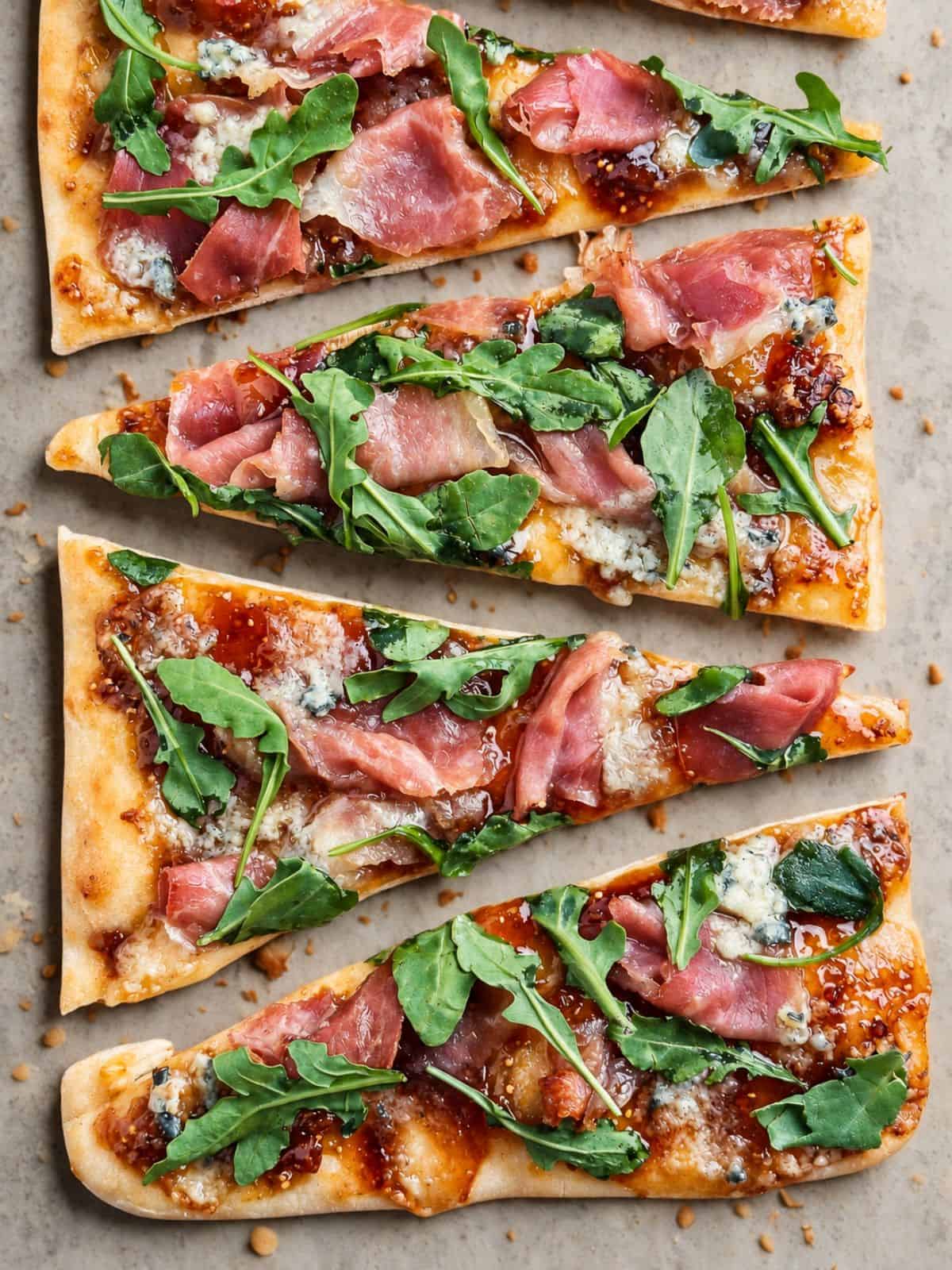 Fresh gourmet pizza slices with arugula, prosciutto, and blue cheese.