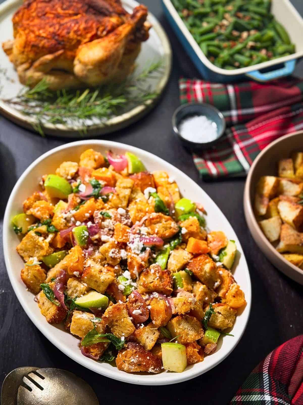 Fall dinner table with fall panzanella salad, roast chicken, potatoes, and green beans.