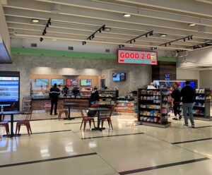 Inside a modern food court with a snack stand and seating area.